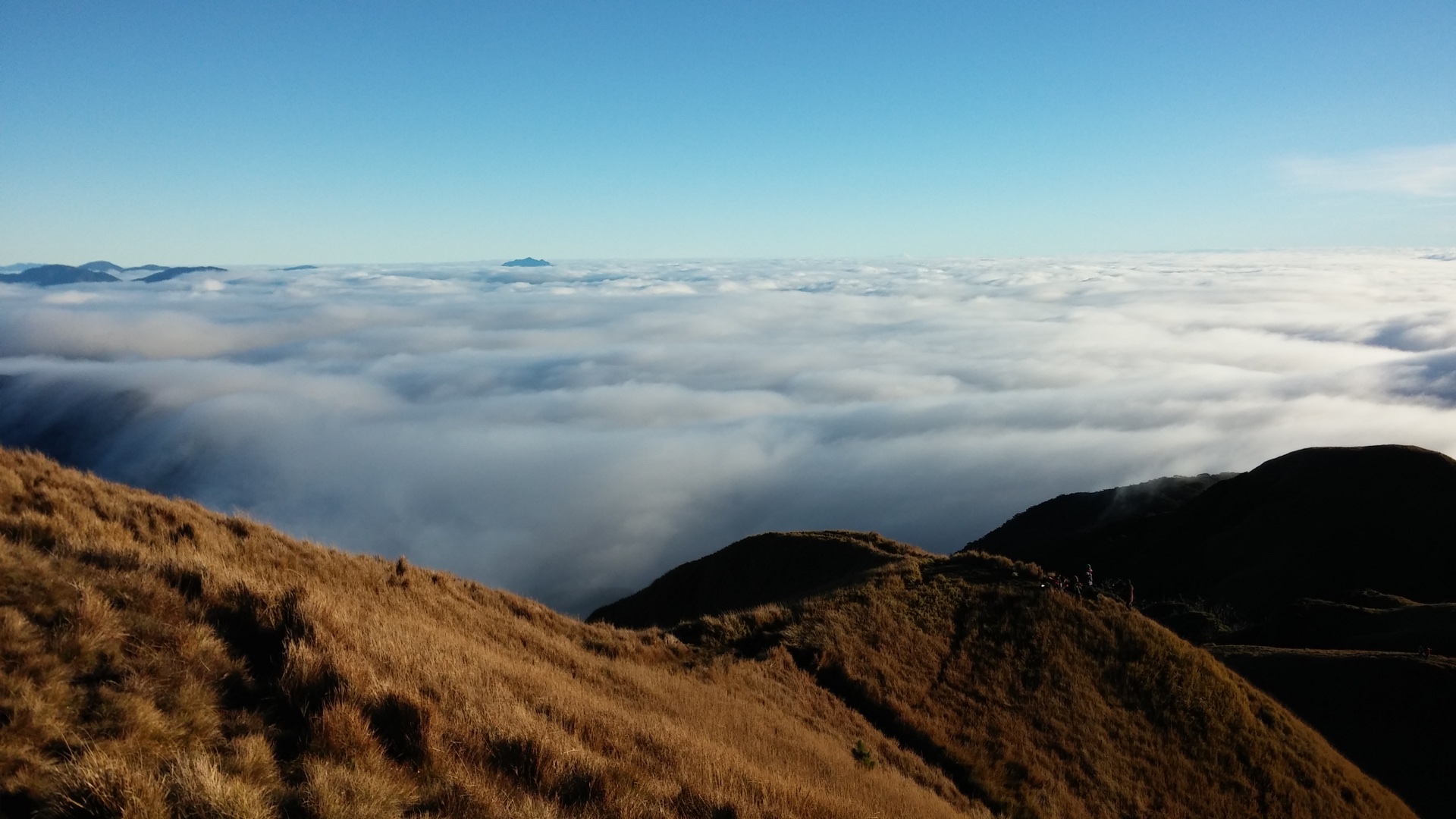 Grass-covered slopes on Mount Pulag beneath a cloudy sky